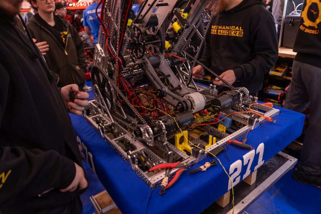 Team 271 Mechanical Marauders students and robot at competitions and in the shop