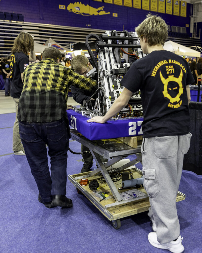 Team 271 Mechanical Marauders students and robot at competitions and in the shop