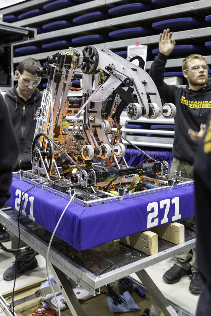 Team 271 Mechanical Marauders students and robot at competitions and in the shop