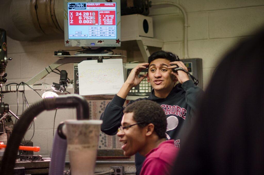 Peter Mathews with teammates at the CNC machine in the team shop