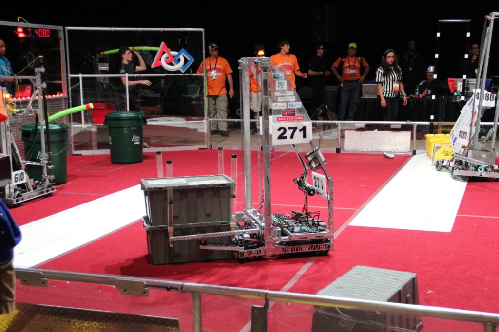 Team 271 2015 robot beside totes on the Championship field